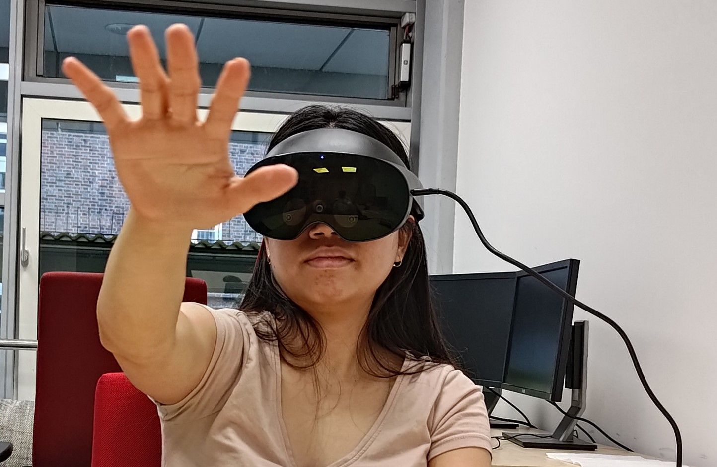 Person wearing a VR headset, reaching their hand out to touch a virtual object not visible in the real world.